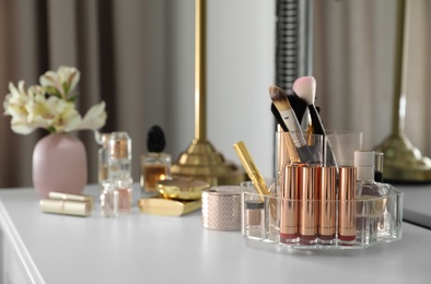 Photo of Luxury makeup products and accessories on dressing table with mirror. Space for text