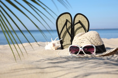 Stylish beach accessories on sand near sea