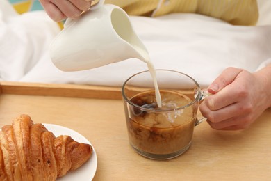 Photo of Woman pouring milk into cup with hot drink in bed, closeup