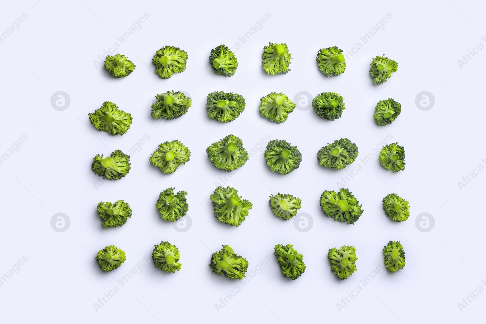 Photo of Many fresh green broccoli pieces on white background, flat lay