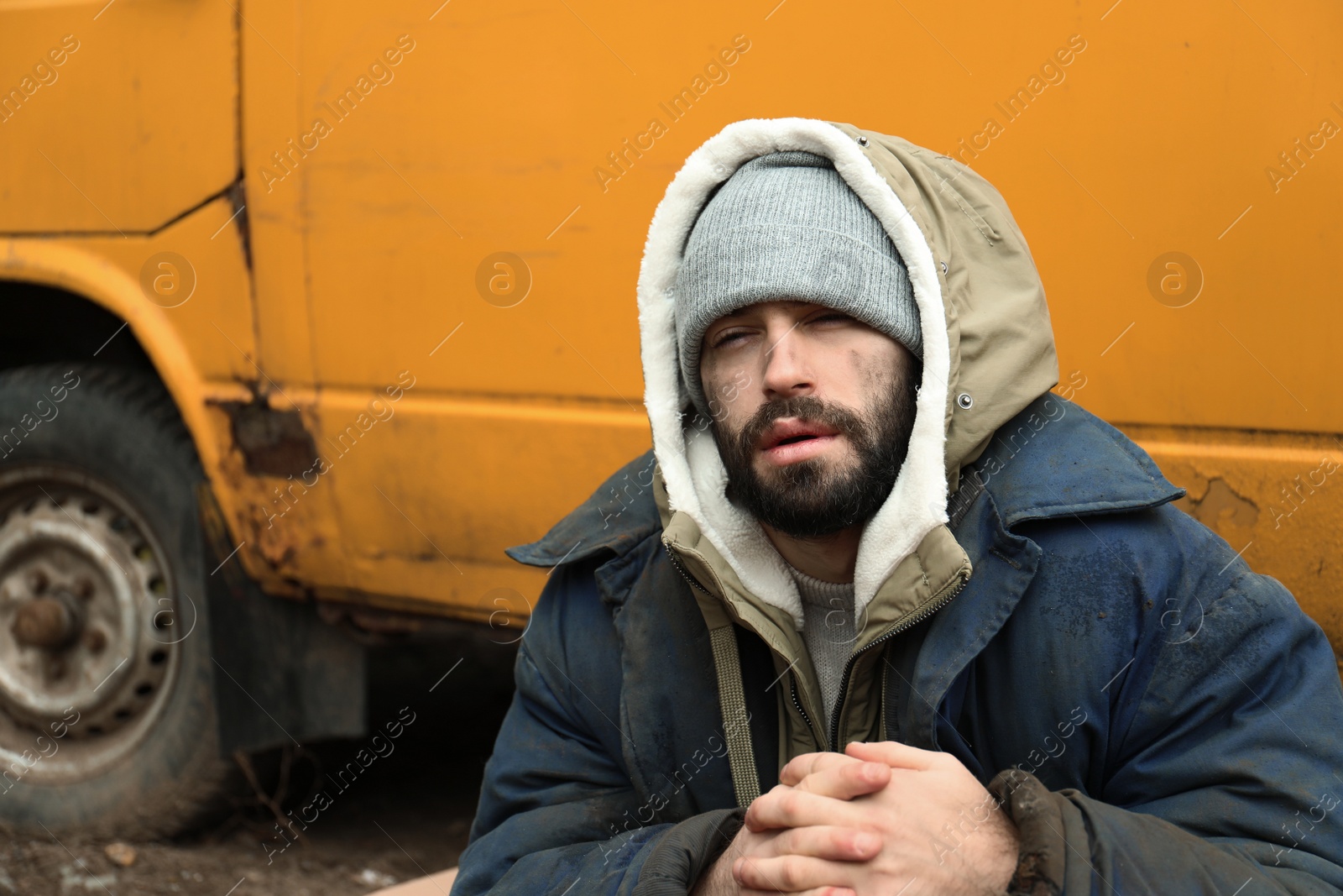 Photo of Poor homeless man sitting near van outdoors