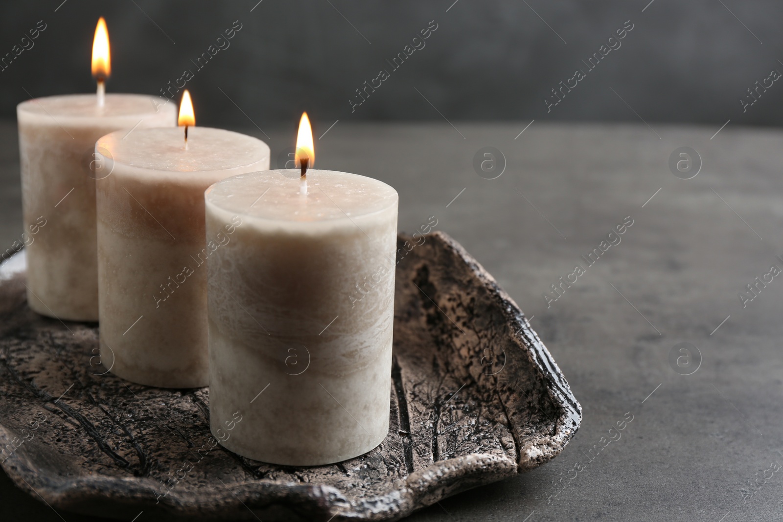 Photo of Tray with three burning candles on table. Space for text