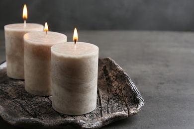 Tray with three burning candles on table. Space for text