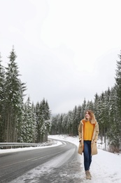 Young woman walking near snowy forest. Winter vacation