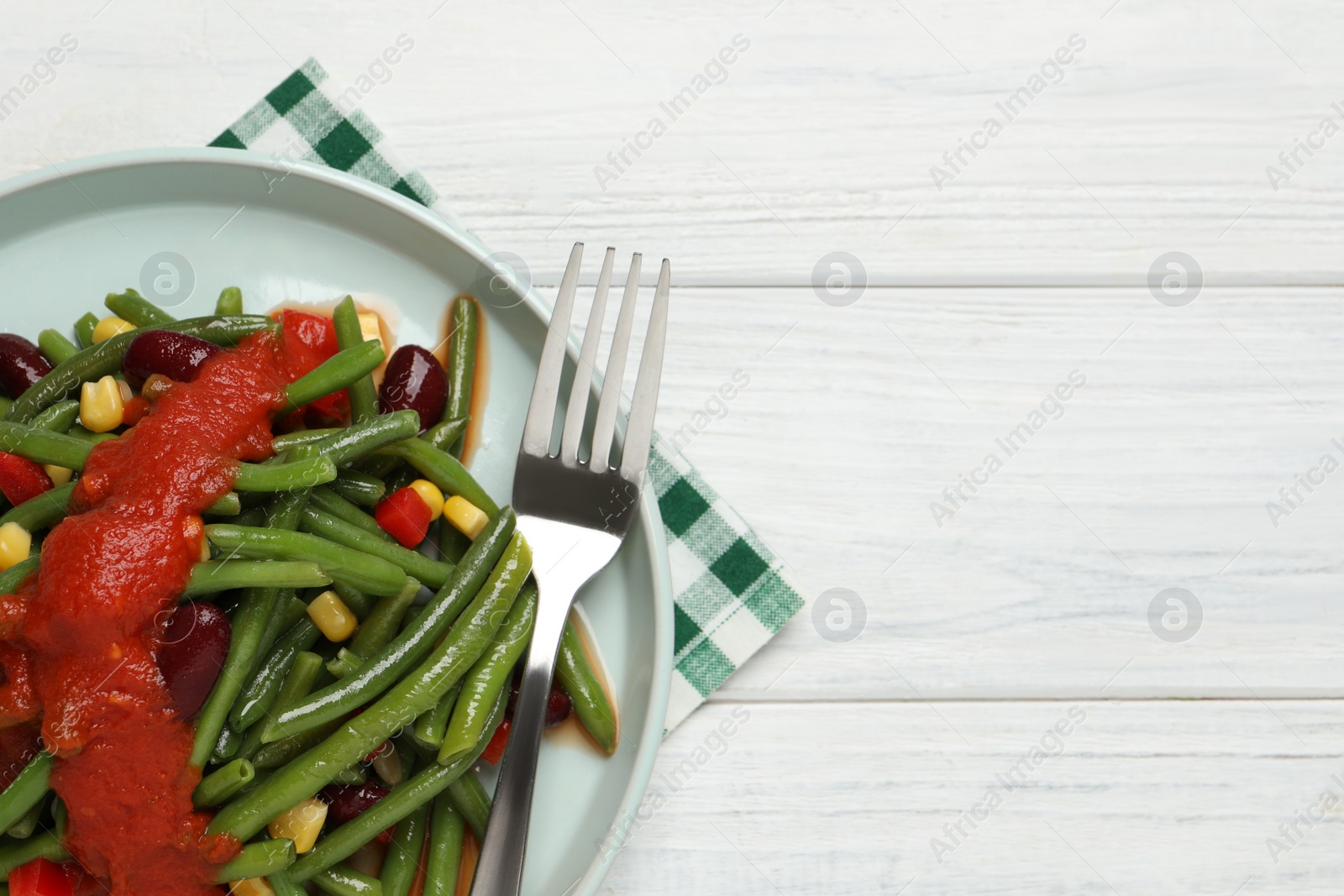 Photo of Delicious salad with green beans and tomato sauce served on white wooden table, top view. Space for text