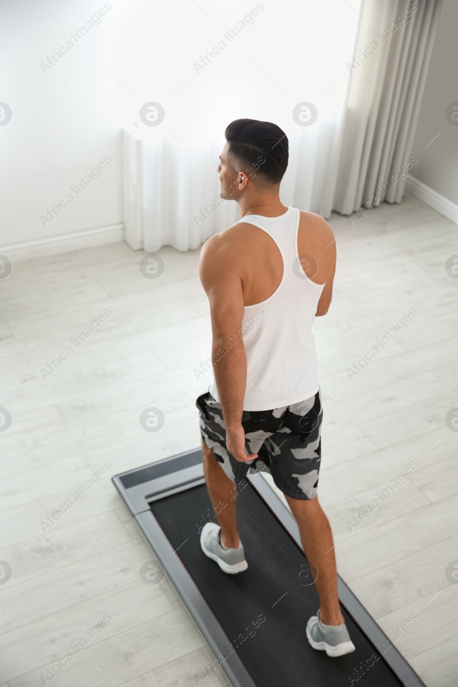 Photo of Sporty man training on walking treadmill at home