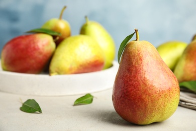 Photo of Ripe juicy pears on white stone table against blue background, closeup. Space for text