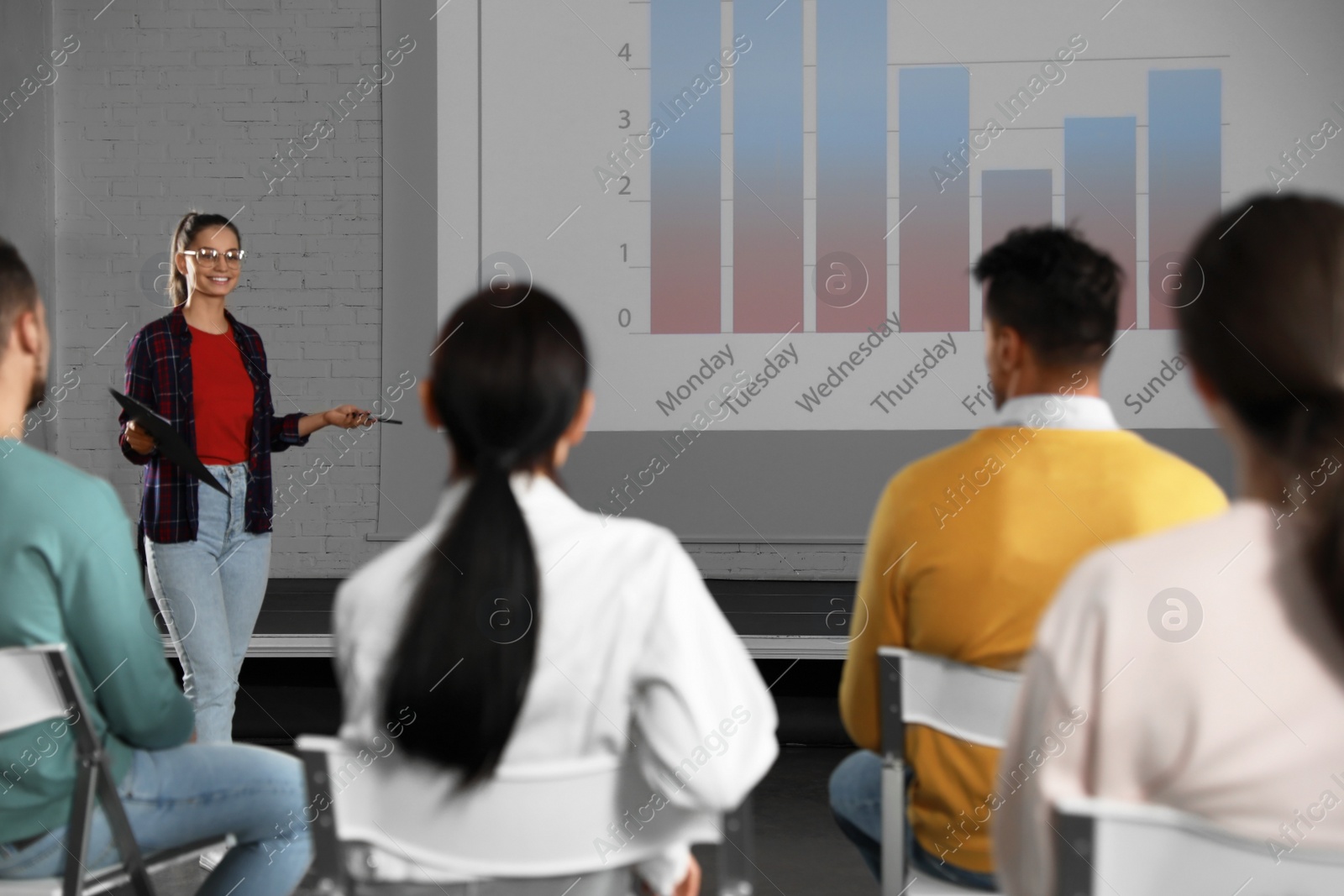 Photo of Female business trainer giving lecture in conference room with projection screen