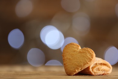 Delicious cookies on wooden table against blurred background, closeup. Space for text