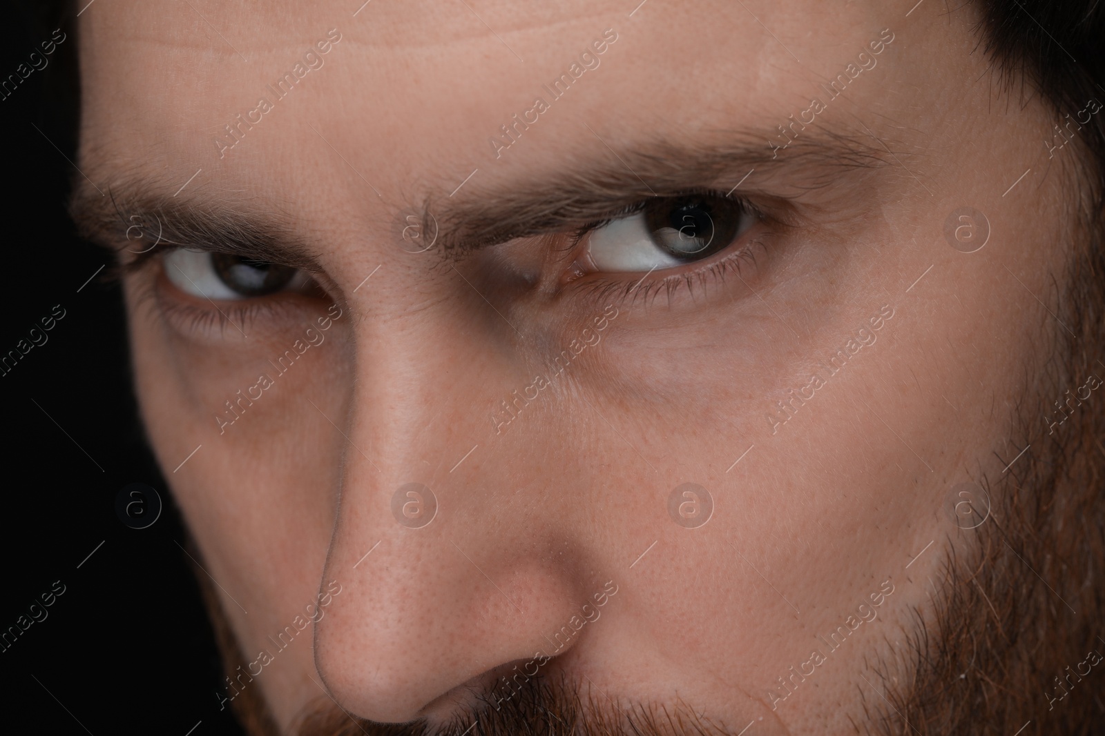 Photo of Evil eye. Man with scary eyes on black background, closeup