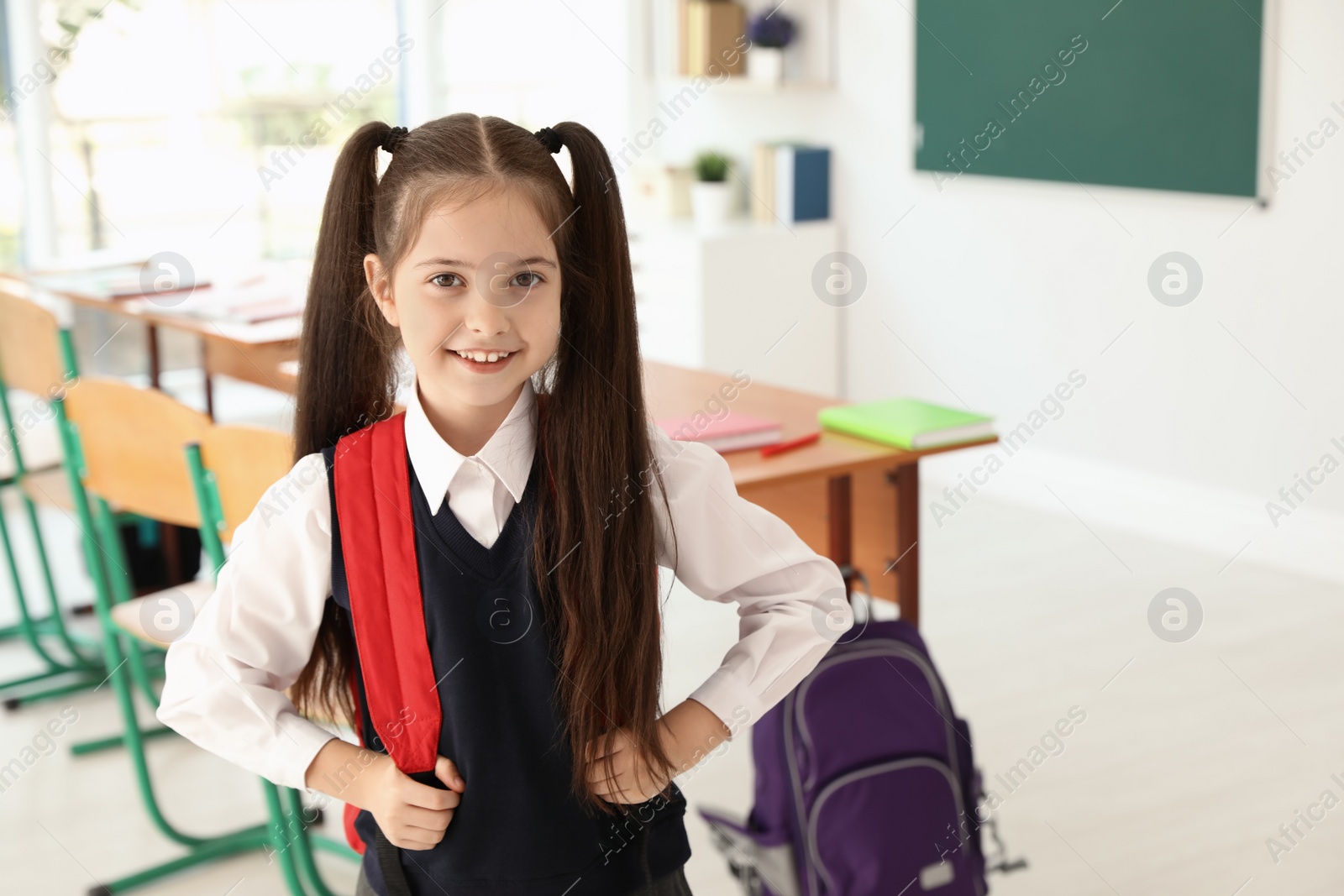 Photo of Little girl in classroom. Stylish school uniform