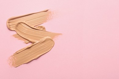 Photo of Sample of liquid skin foundation on pink background, top view. Space for text