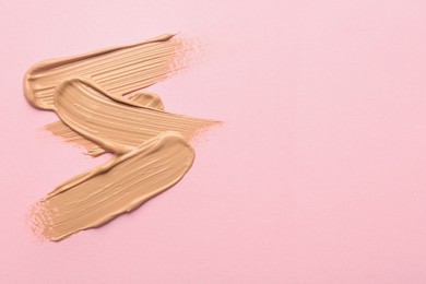 Sample of liquid skin foundation on pink background, top view. Space for text