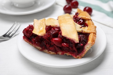 Slice of delicious fresh cherry pie on white wooden table, closeup