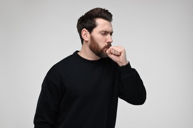 Photo of Sick man coughing on light grey background. Cold symptoms