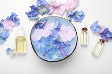 Photo of Spa composition. Aromatic water in bowl, flowers and bottles of essential oil on white background, flat lay