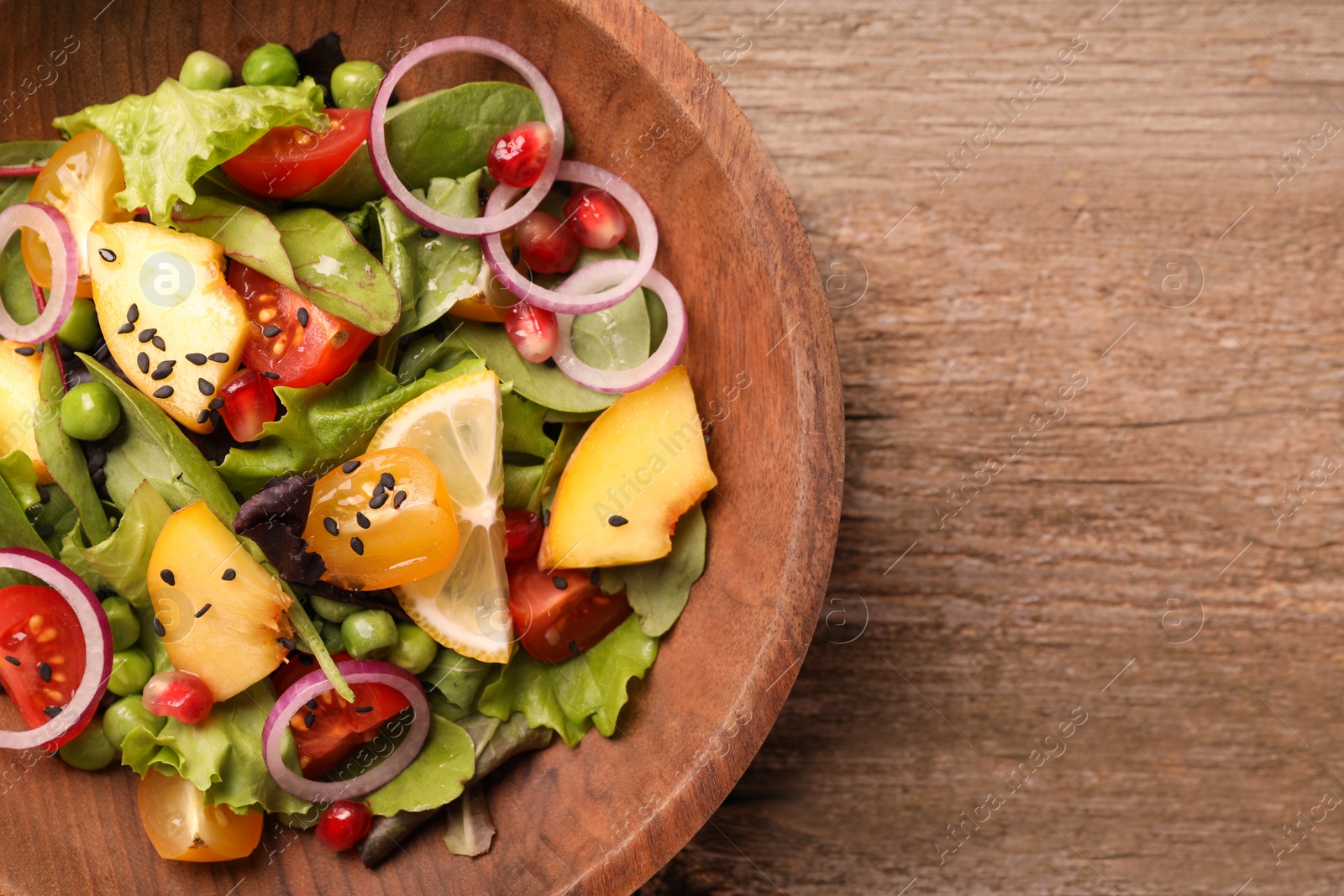 Photo of Delicious salad with peach, green peas and vegetables in bowl on wooden table, top view. Space for text