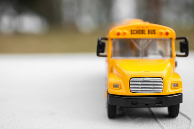 Closeup view of yellow toy school bus outdoors, space for text. Transport for students