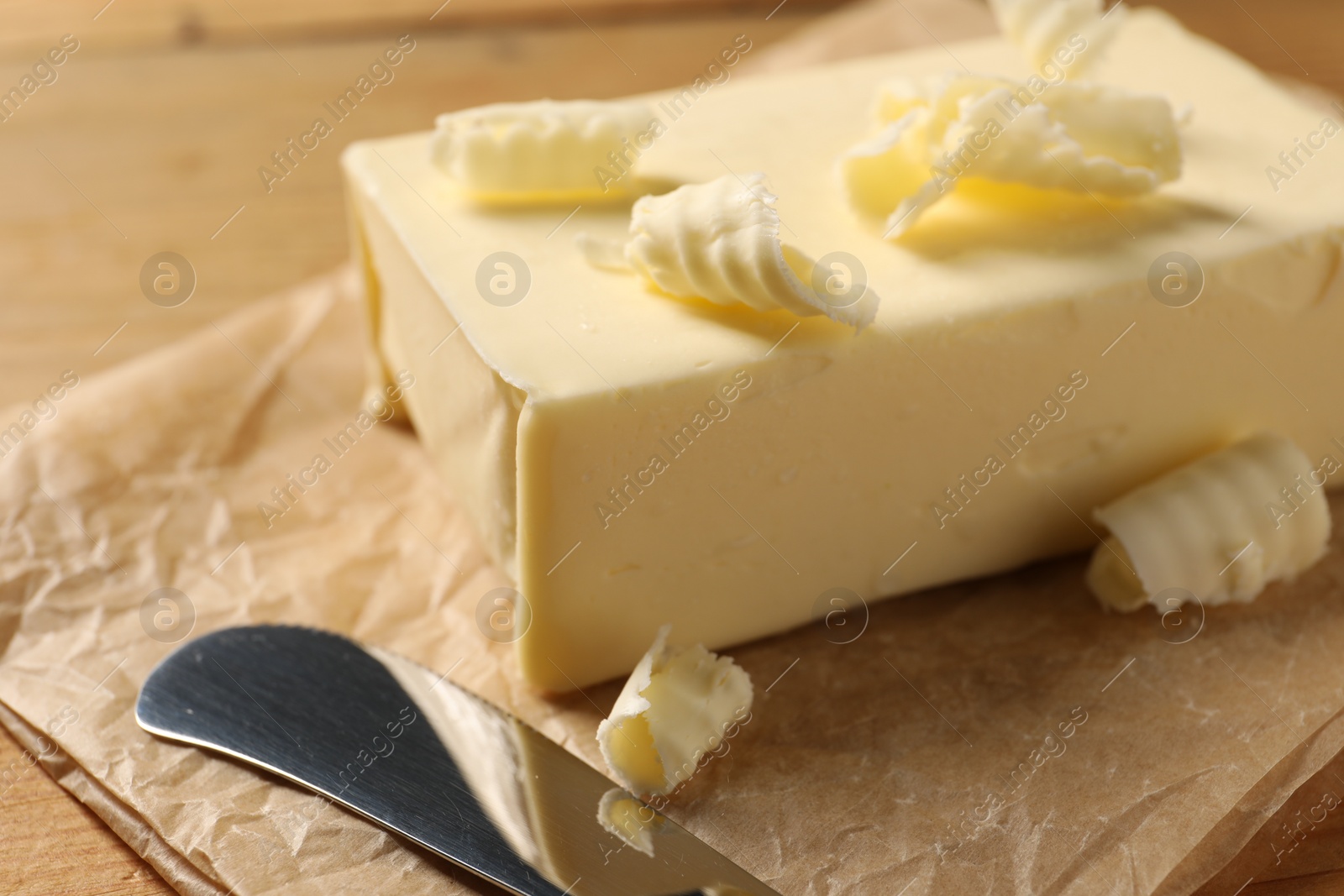 Photo of Tasty butter and knife on wooden table, closeup