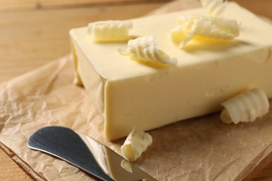 Photo of Tasty butter and knife on wooden table, closeup