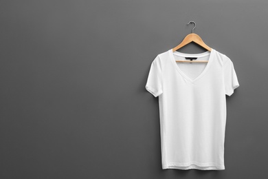 Photo of Hanger with blank t-shirt on grey background. Mockup for design