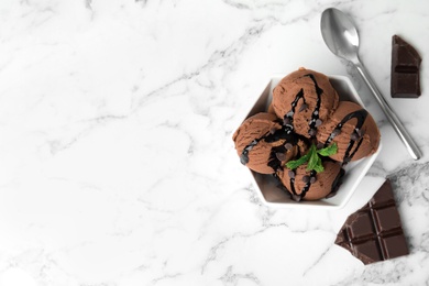Flat lay composition with bowl of chocolate ice cream served on marble table, space for text