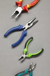 Different pliers on grey background, flat lay