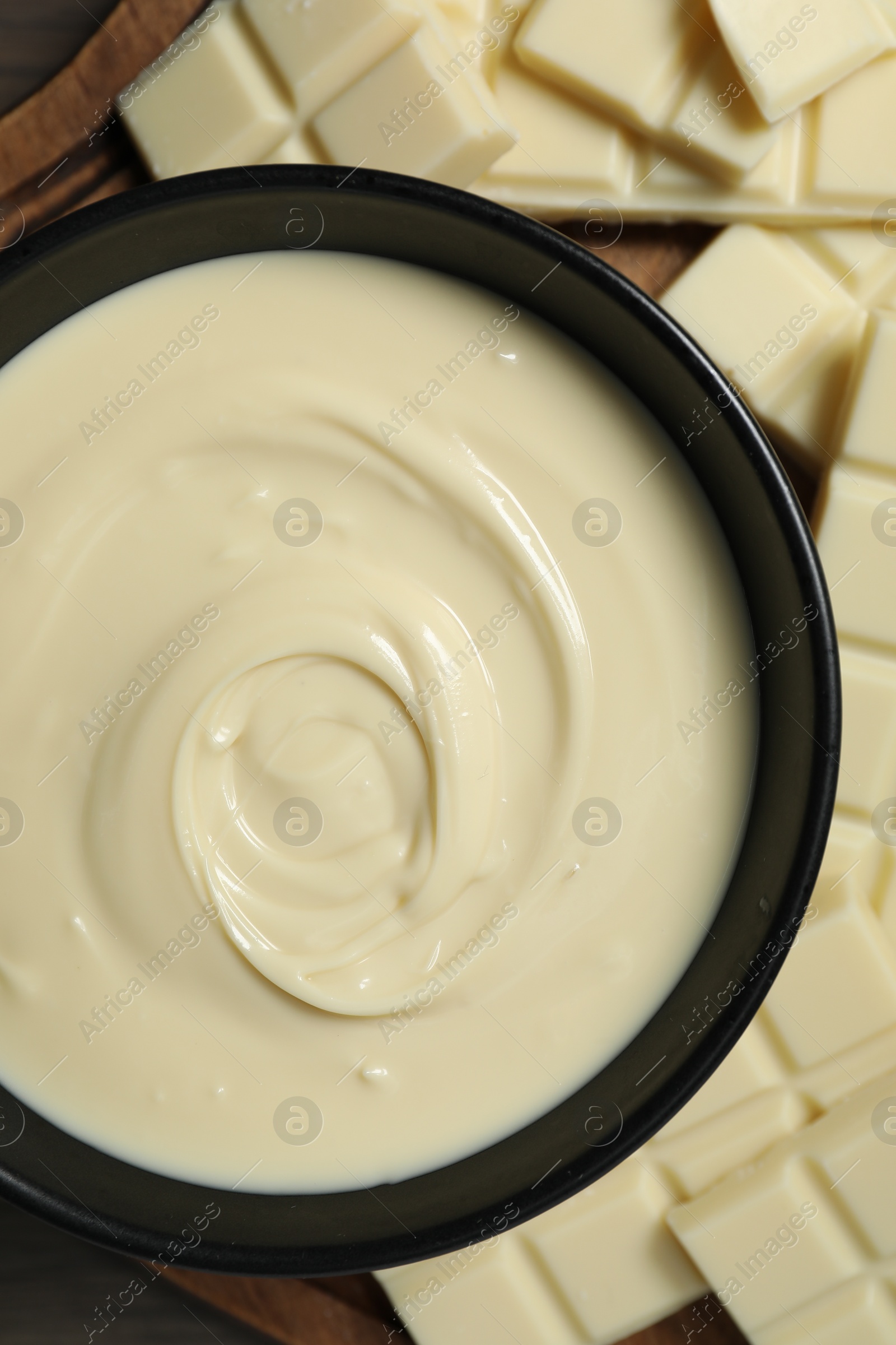 Photo of Tasty white chocolate paste in bowl and pieces on table, top view