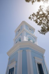 Photo of Beautiful tower with clock against blue sky, low angle view