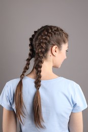 Woman with braided hair on grey background, back view