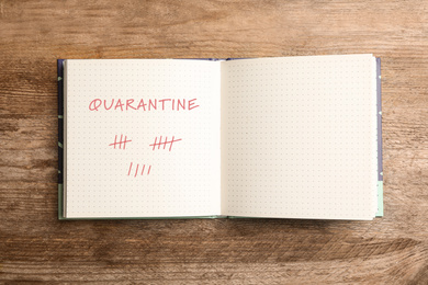 Open notebook on wooden table, top view. Counting days of quarantine during coronavirus outbreak 