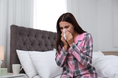 Photo of Young woman suffering from allergy in bedroom