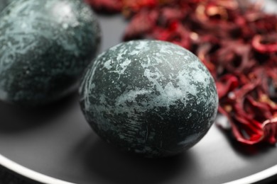 Photo of Naturally painted Easter eggs on black plate, closeup. Hibiscus used for coloring