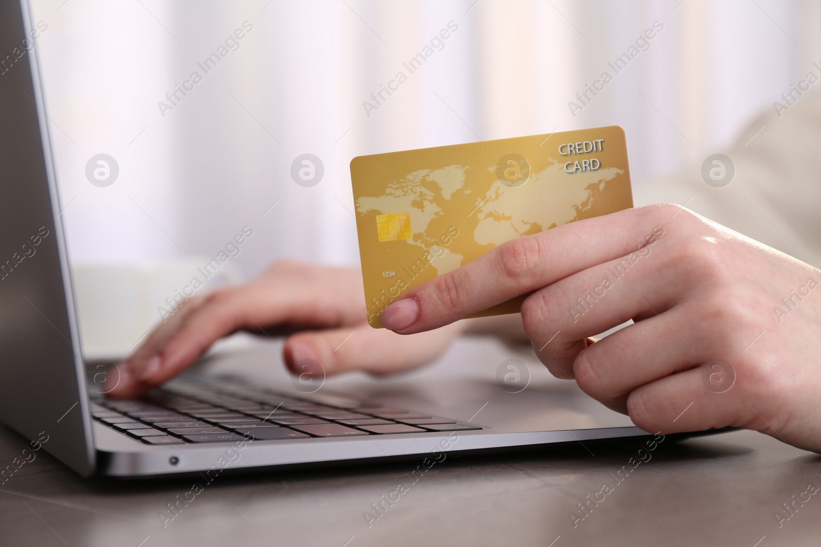 Photo of Online payment. Woman with laptop and credit card at grey table, closeup