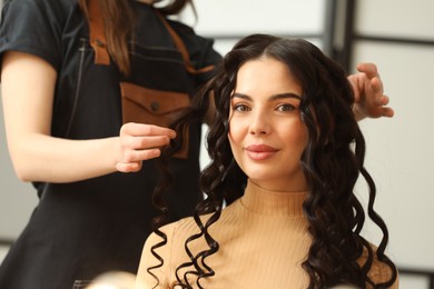 Photo of Hair styling. Professional hairdresser working with client indoors, closeup