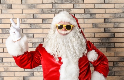 Authentic Santa Claus wearing sunglasses on brick wall background