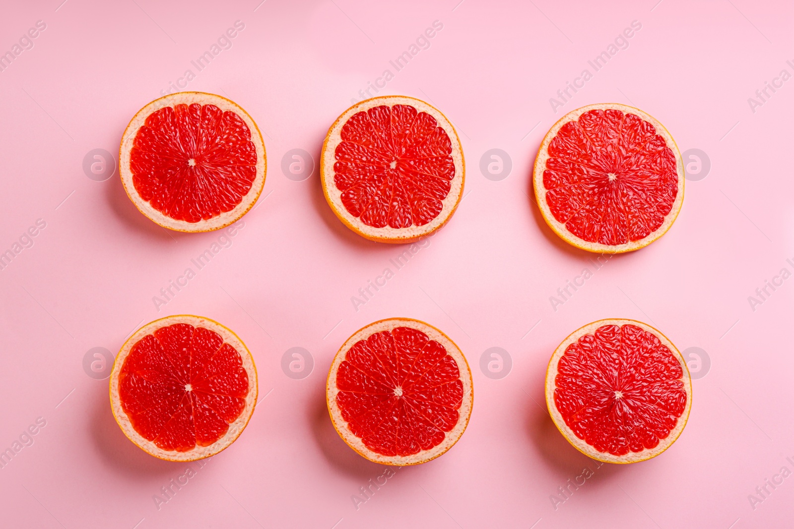 Photo of Tasty ripe grapefruit slices on pink background, flat lay