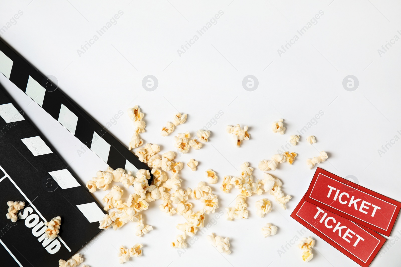 Photo of Clapperboard, popcorn and tickets isolated on white, top view. Cinema snack