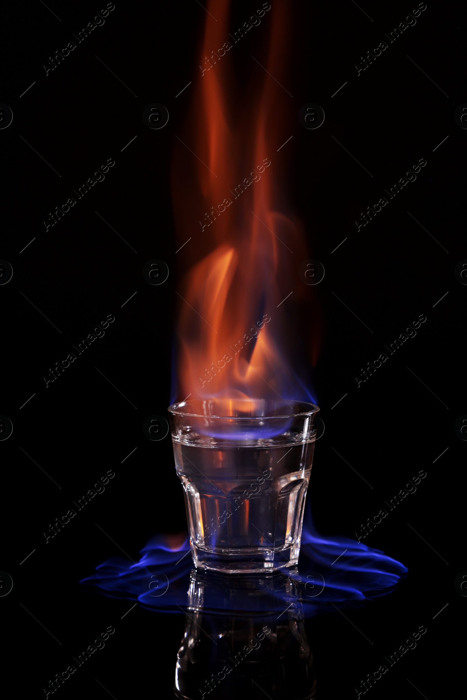 Photo of Flaming vodka in shot glass on black background