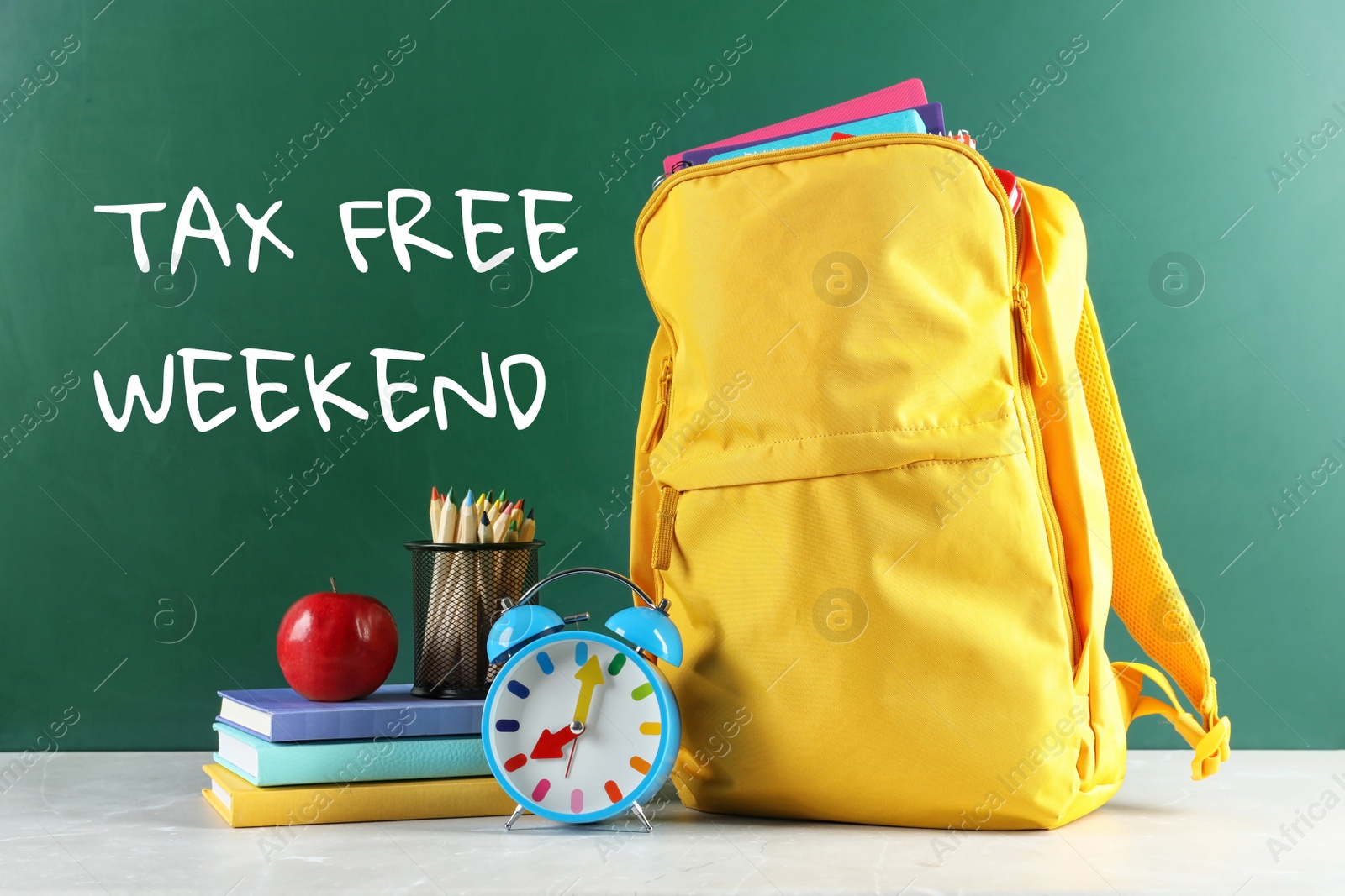 Image of Backpack with school stationery and text TAX FREE WEEKEND written on chalkboard in classroom