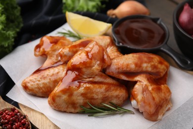 Photo of Raw marinated chicken wings and spices on table, closeup