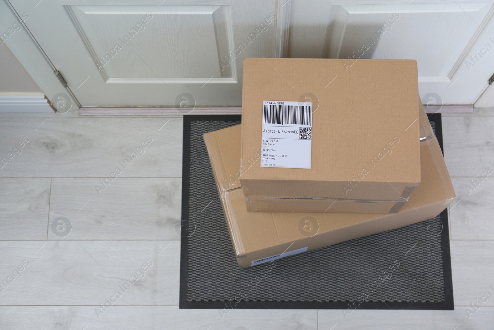 Photo of Cardboard boxes on rug near door, top view. Parcel delivery service