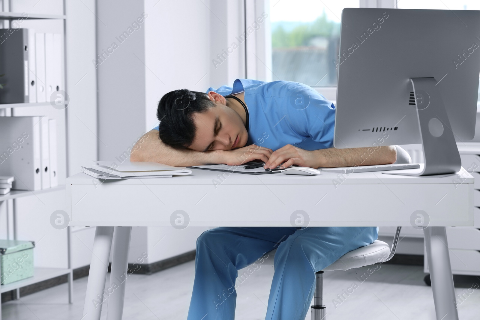 Photo of Exhausted doctor sleeping at workplace in hospital