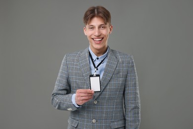 Happy man with blank badge on grey background