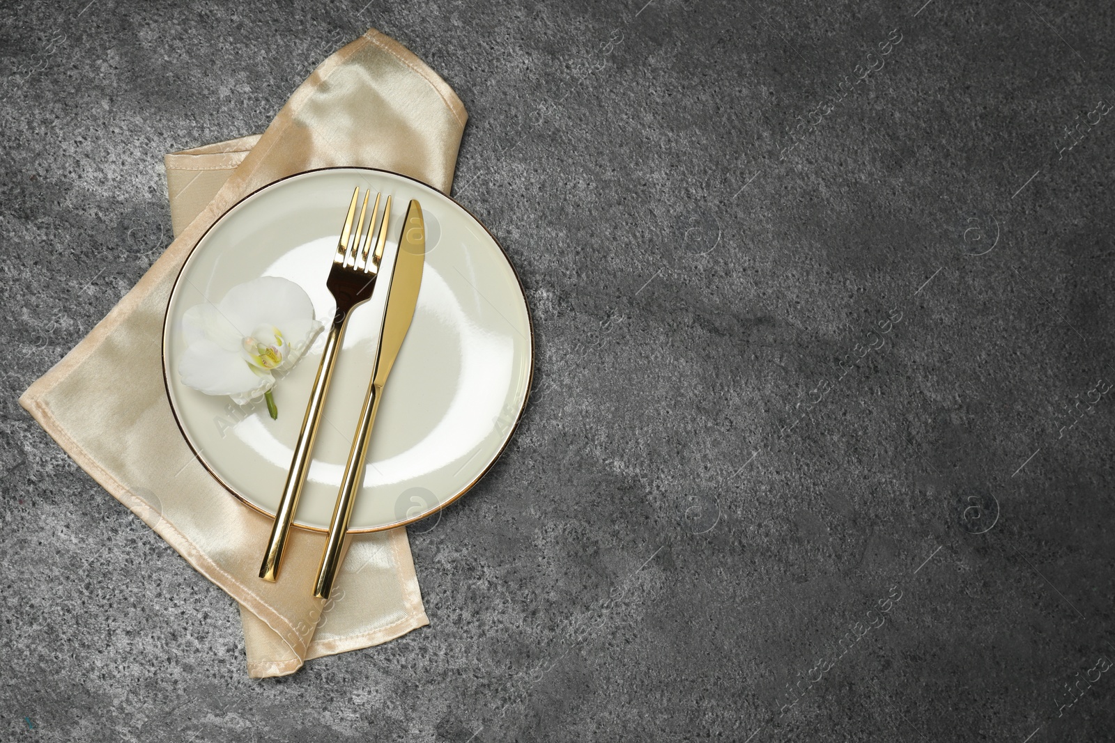 Photo of Stylish setting with elegant cutlery on grey table, top view. Space for text