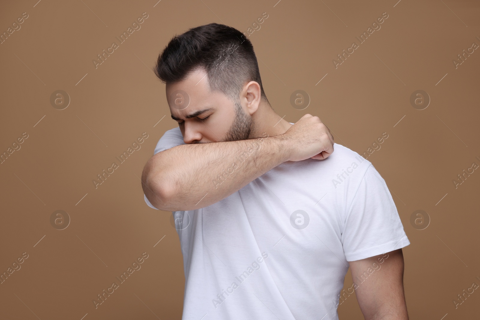 Photo of Sick man coughing on brown background. Cold symptoms