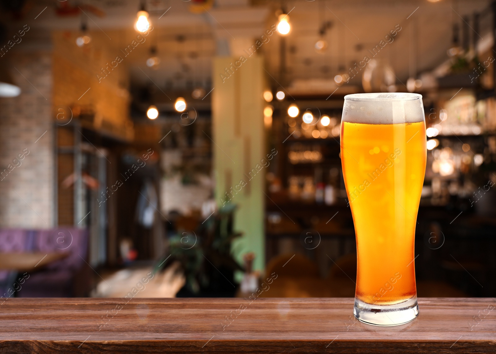 Image of Glass with cold tasty beer on wooden table in pub, space for text