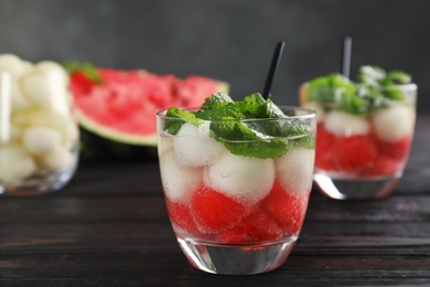 Photo of Glass with tasty melon and watermelon ball drink on dark table