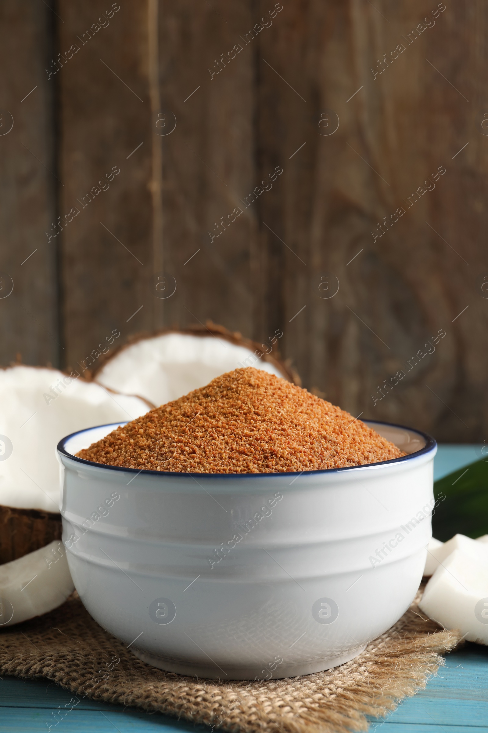 Photo of Natural coconut sugar in bowl on blue wooden table