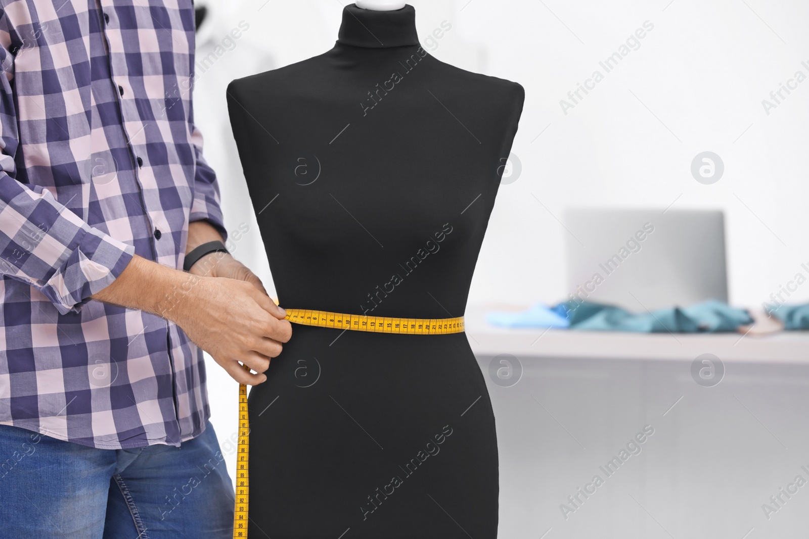 Photo of Tailor measuring mannequin in workshop, closeup